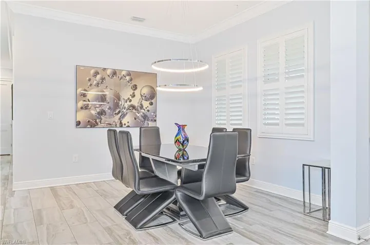 Dining room with an inviting chandelier, crown molding, and light hardwood / wood-style floors