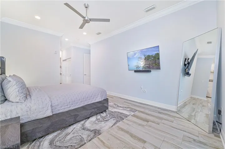 Bedroom with crown molding, ceiling fan, and light hardwood / wood-style flooring