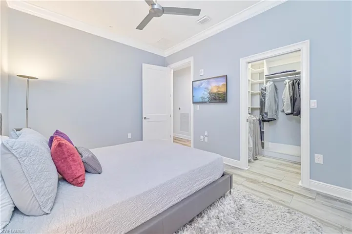 Bedroom with light hardwood / wood-style flooring, a closet, ceiling fan, and ornamental molding