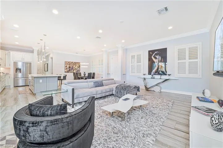 Living room featuring ornamental molding, light hardwood / wood-style floors, decorative columns, and sink