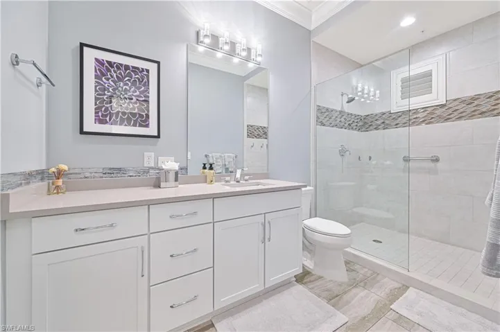 Bathroom with crown molding, a tile shower, vanity, and toilet