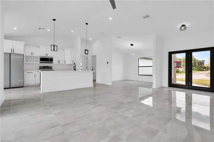 Unfurnished living room featuring high vaulted ceiling and french doors