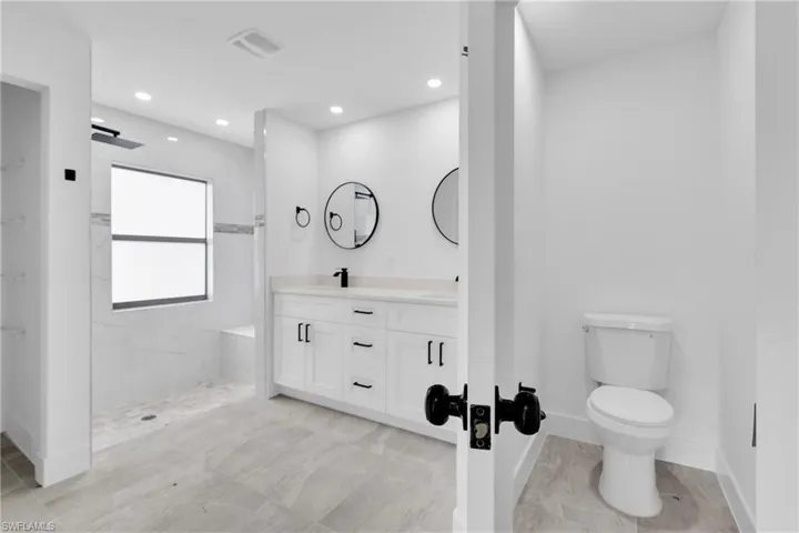 Bathroom with double vanity, a marble finish shower, and recessed lighting