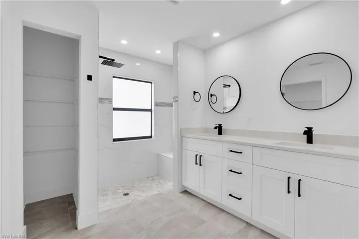 Full bathroom featuring a marble finish shower, double vanity, recessed lighting, and a spacious closet
