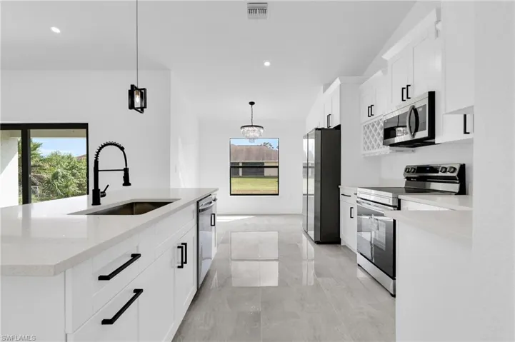 Kitchen featuring stainless steel appliances, white cabinetry, hanging light fixtures, a kitchen island with sink, and recessed lighting