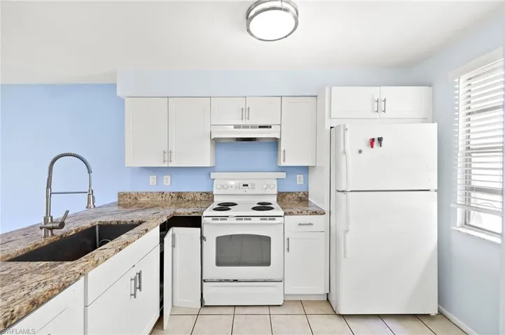 Kitchen featuring white appliances, white cabinetry, and sink