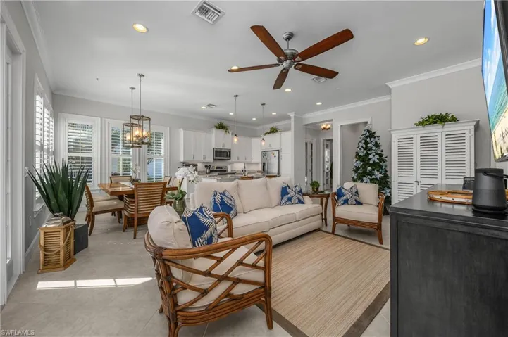 Living room featuring ornamental molding, a ceiling fan, recessed lighting, and a chandelier