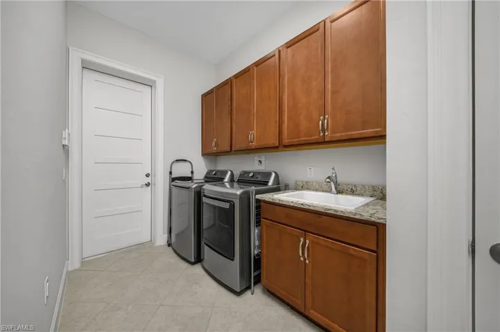 Washroom featuring cabinet space, washing machine and dryer, and light tile patterned floors