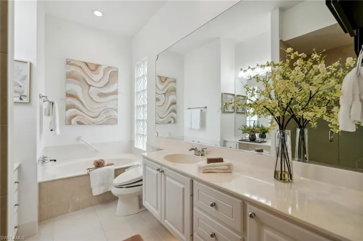 Her Master Bathroom featuring tile patterned flooring, vanity, tiled bath, and toilet