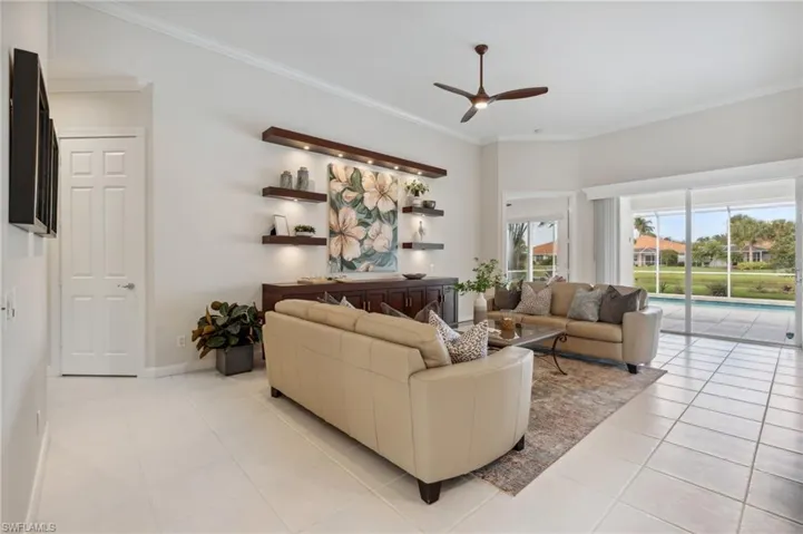 Living room with ceiling fan, light tile patterned floors, and ornamental molding
