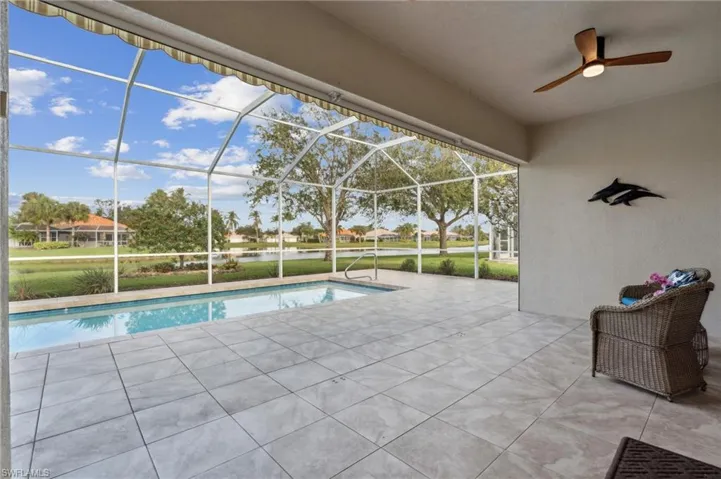 View of swimming pool featuring a patio, glass enclosure, and ceiling fan