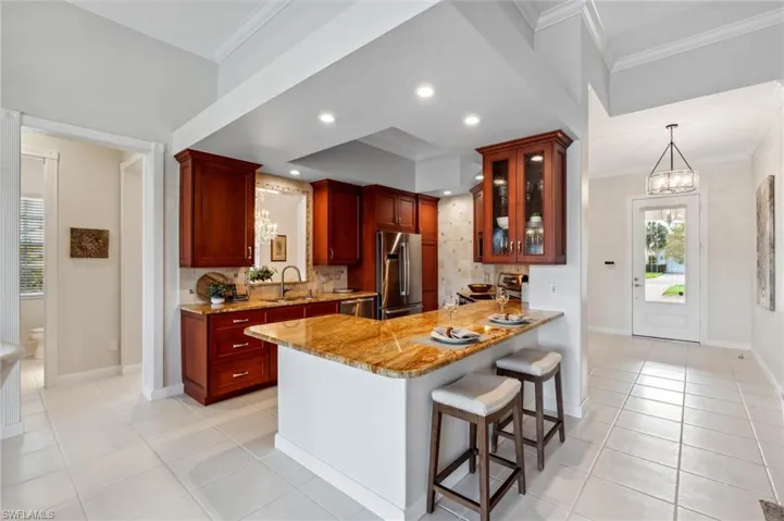 Kitchen with sink, ornamental molding, appliances with stainless steel finishes, tasteful backsplash, and light stone counters