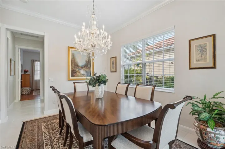 Dining room with light tile patterned floors, a notable chandelier, and ornamental molding