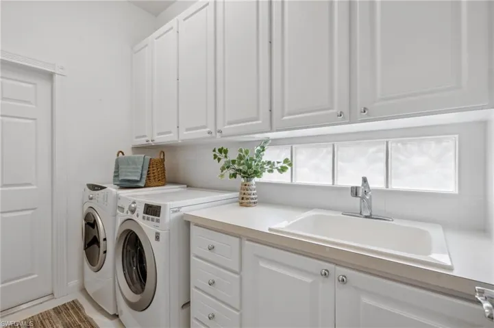 Washroom with washer and dryer, sink, and cabinets