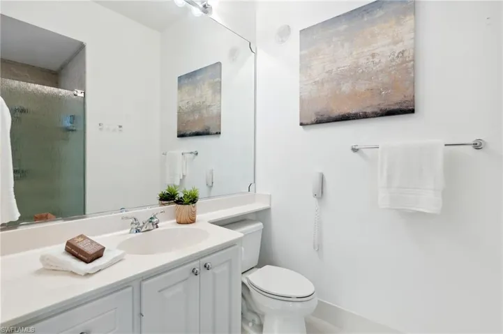 His Master Bathroom featuring an enclosed shower, vanity, and toilet