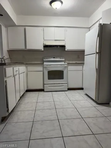 Kitchen featuring refrigerator, white cabinets, white electric range oven, and ventilation hood