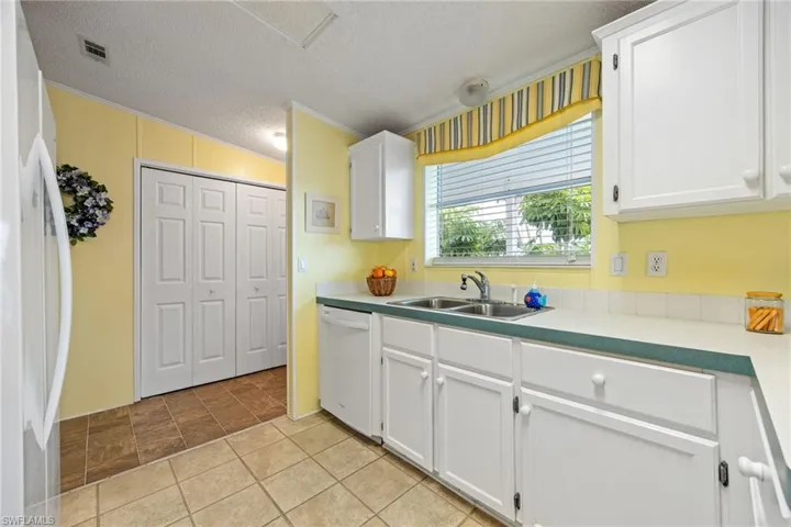 Kitchen with white appliances, white cabinetry, crown molding, light countertops, and a textured ceiling