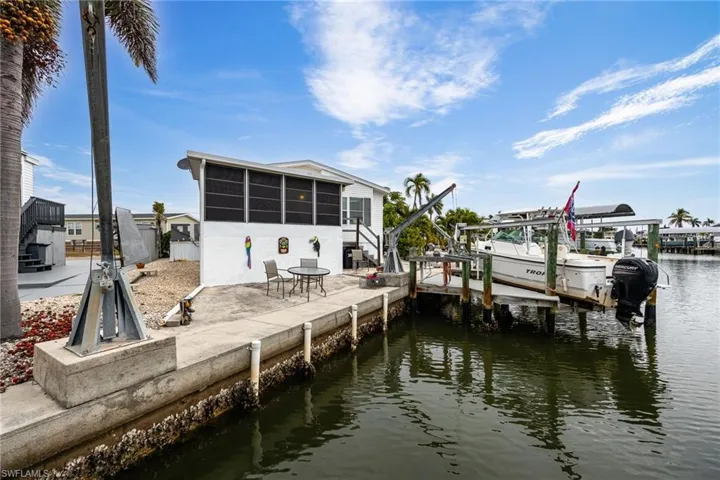 Dock with boat lift, seawall, davits, a sunroom, and stairway