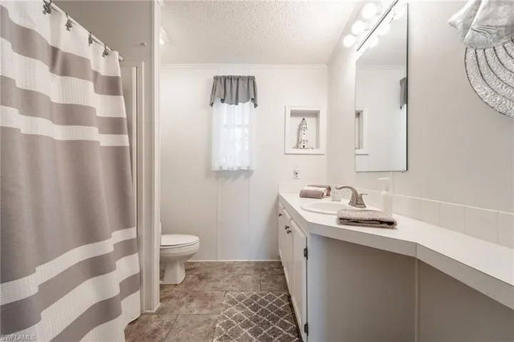 Full bath with vanity, a textured ceiling, a shower with curtain, and crown molding