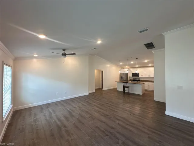 Unfurnished living room featuring ornamental molding, dark wood-style floors, a ceiling fan, vaulted ceiling, and recessed lighting