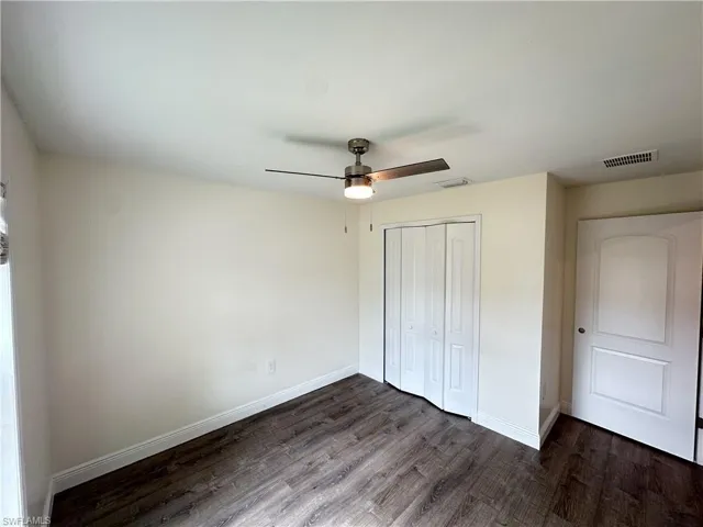 Unfurnished bedroom featuring dark wood-style flooring, ceiling fan, and a closet