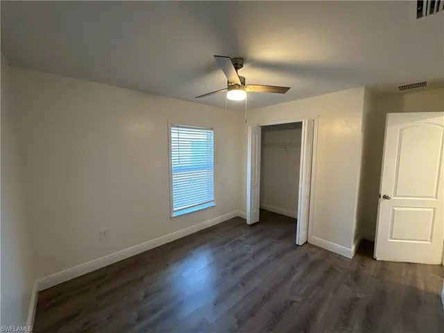 Unfurnished bedroom with dark wood-type flooring, a closet, and a ceiling fan
