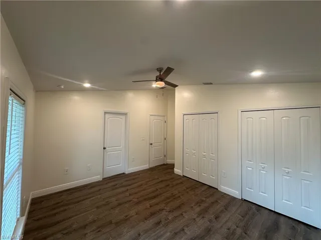 Unfurnished bedroom featuring two closets, dark wood-type flooring, ceiling fan, and recessed lighting