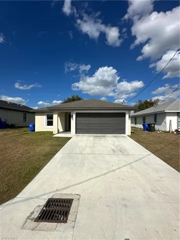 Ranch-style home with a front lawn, driveway, a garage, and stucco siding