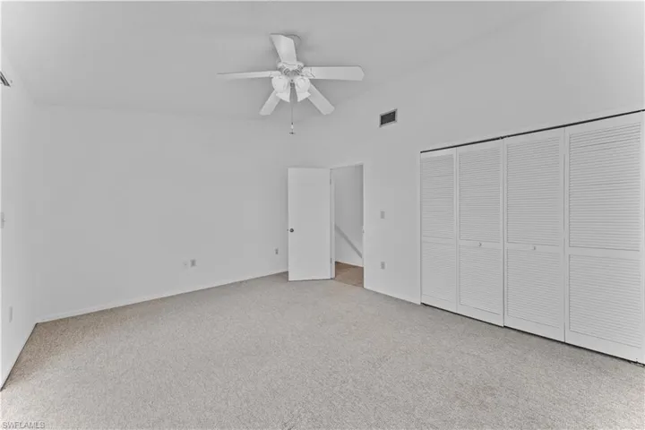 Unfurnished bedroom with light colored carpet, ceiling fan, and a closet