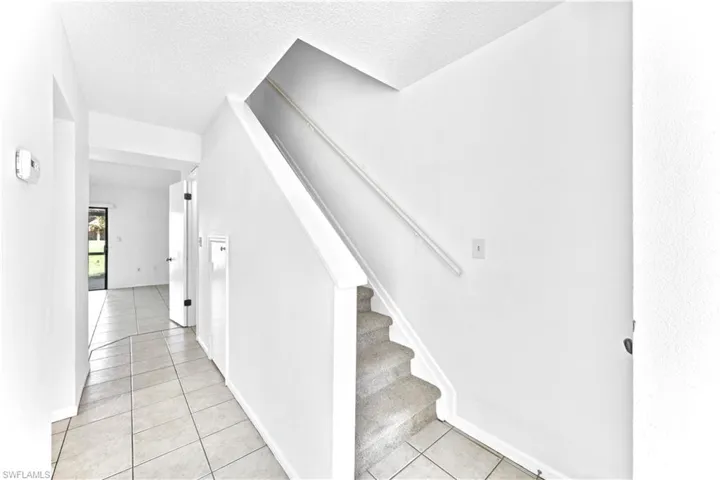 Staircase featuring tile patterned floors and a textured ceiling