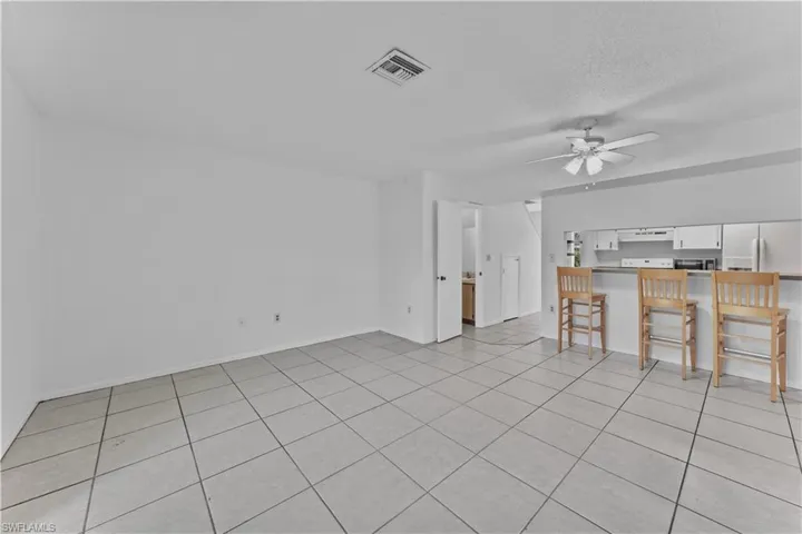 Unfurnished living room featuring a textured ceiling, light tile patterned floors, and ceiling fan