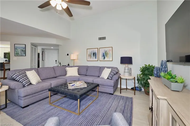 Living area featuring light wood finished floors, visible vents, ceiling fan, high vaulted ceiling, and baseboards