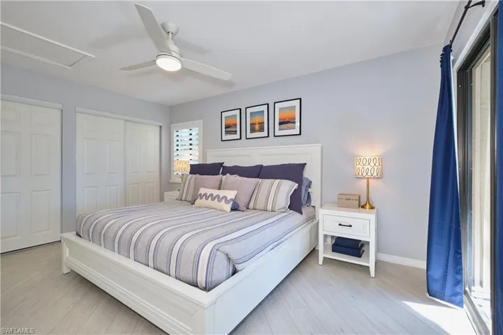 Bedroom featuring two closets, lighted ceiling fan, and wood-style LTV floors.