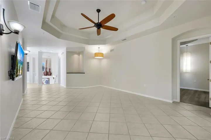 Tray ceiling with a ceiling fan, recessed lighting, tile flooring, and an arched doorway