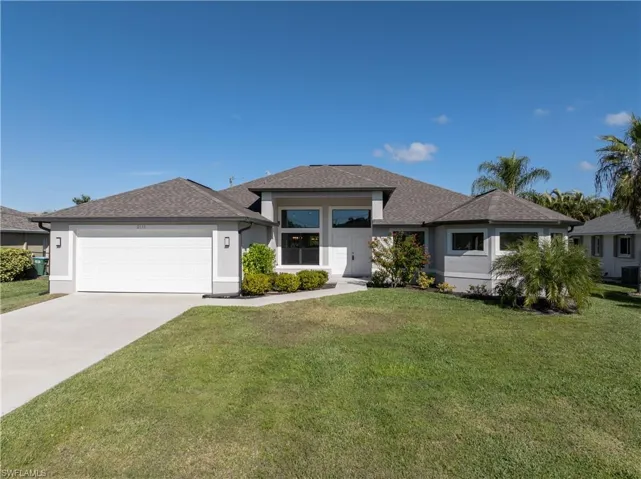 Prairie-style house with a front yard, driveway, stucco siding, and roof with shingles