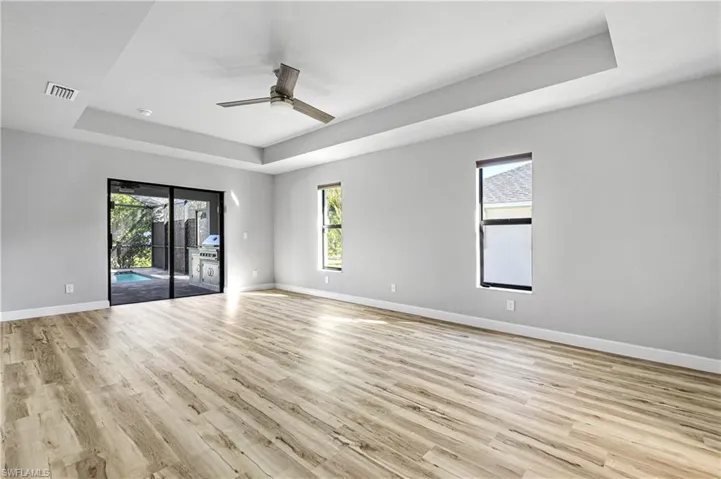 Spare room featuring a raised ceiling, light wood-style floors, and ceiling fan