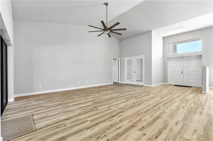 Unfurnished living room featuring high vaulted ceiling, light wood finished floors, and a ceiling fan