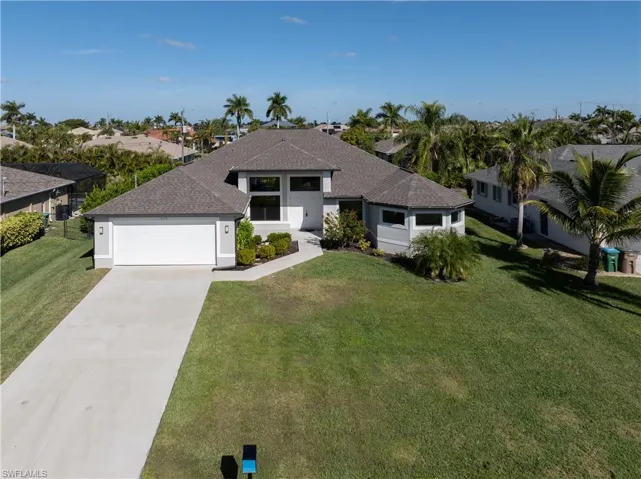 View of front of property with concrete driveway, a front yard, an attached garage, roof with shingles, and stucco siding