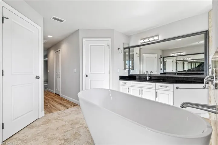 Bathroom featuring a soaking tub, vanity, recessed lighting, and light tile patterned floors