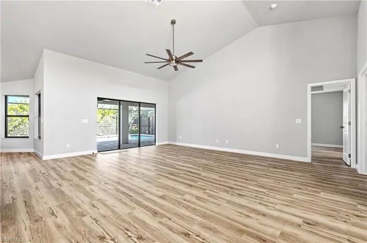 Unfurnished living room with high vaulted ceiling, light wood-style flooring, and a ceiling fan