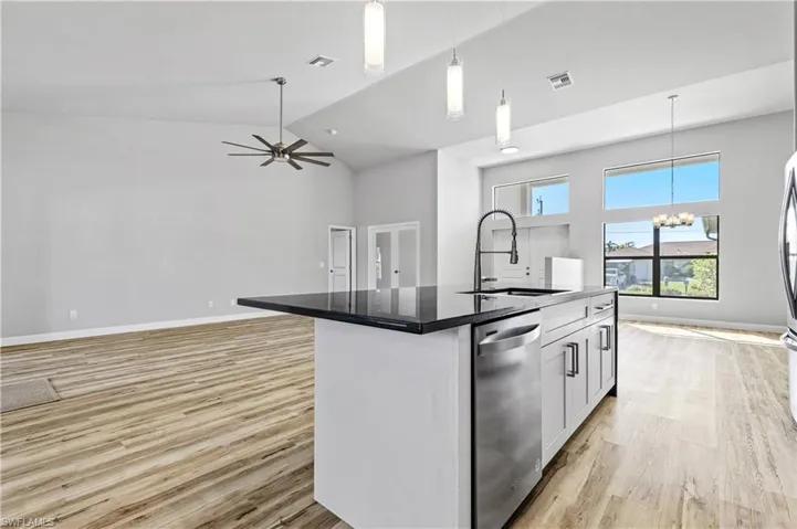 Kitchen featuring pendant lighting, open floor plan, dishwasher, light wood finished floors, and high vaulted ceiling