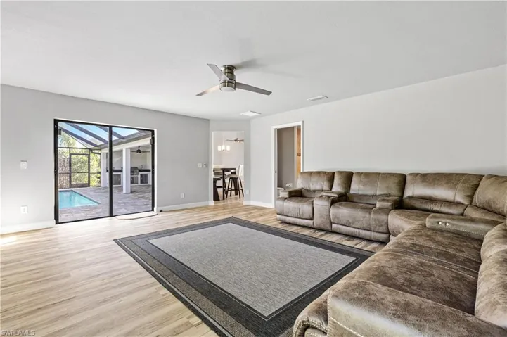 Living area with light wood-type flooring, a sunroom, and a ceiling fan