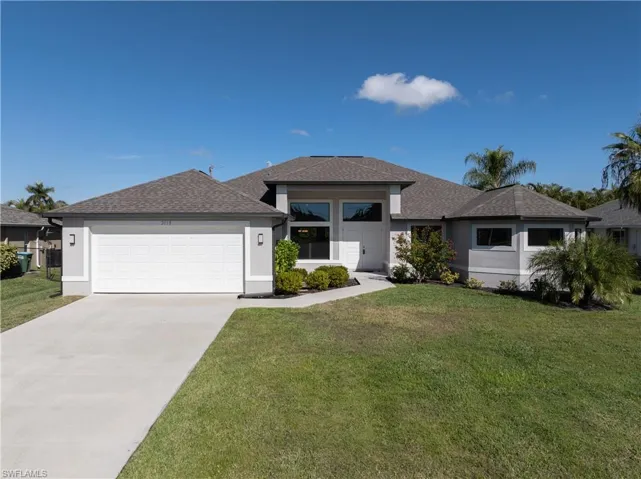 Prairie-style house with stucco siding, roof with shingles, driveway, and a front lawn