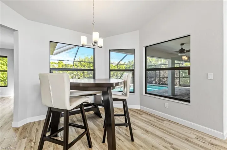 Dining space featuring a sunroom, light wood-type flooring, ceiling fan, and vaulted ceiling