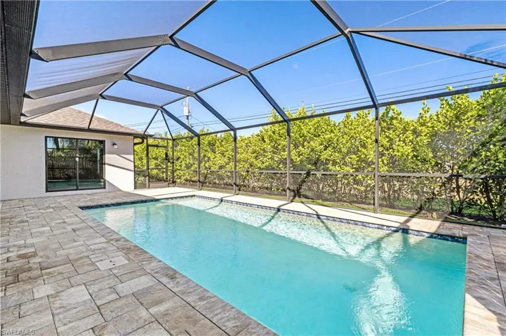 Outdoor pool with a sunroom, glass enclosure, and a patio