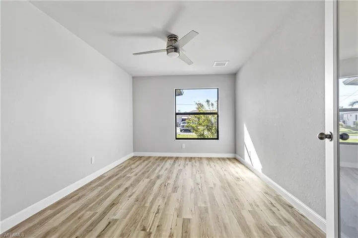 Spare room featuring light wood finished floors, ceiling fan, and a textured wall