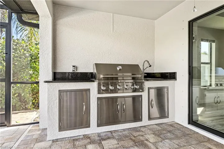 View of patio with an outdoor kitchen, a sunroom, and a lanai