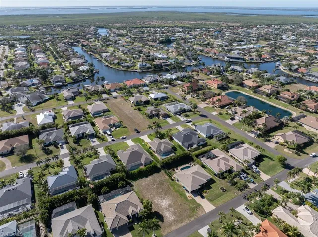 Aerial view of property and surrounding area featuring nearby suburban area and a large body of water