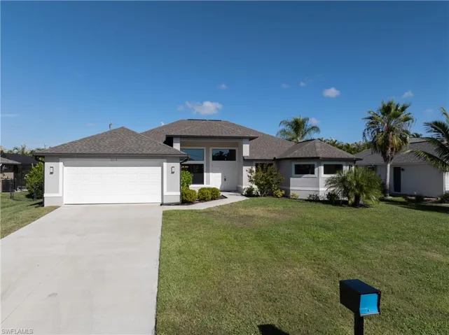 Prairie-style house with driveway, stucco siding, roof with shingles, and a front yard