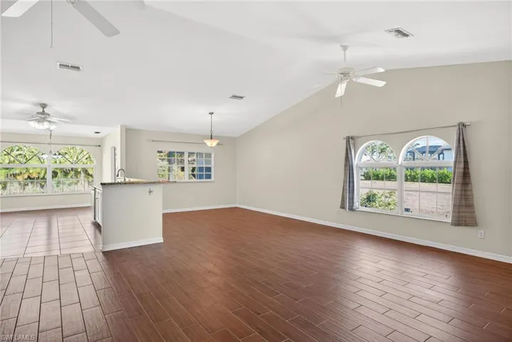 Unfurnished living room with a ceiling fan, wood tiled floors, and a high ceiling